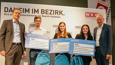 3 junge Menschen halten Schecks in den Händen und stehen vor einem WKO Banner
